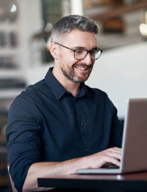 A man with beard and glasses working on a laptop