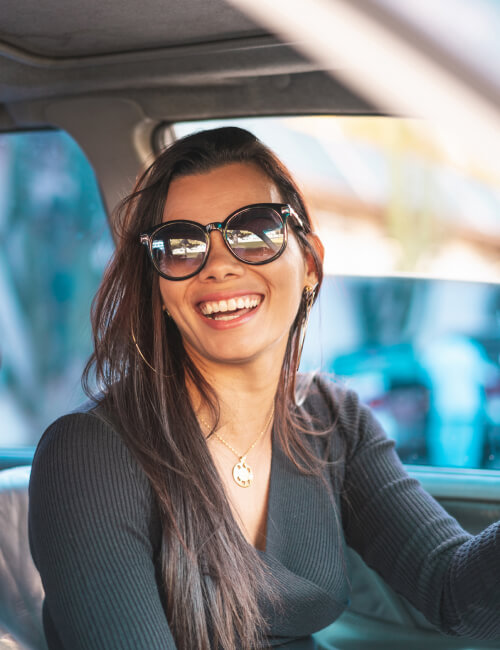 A woman wearing glasses in her car
