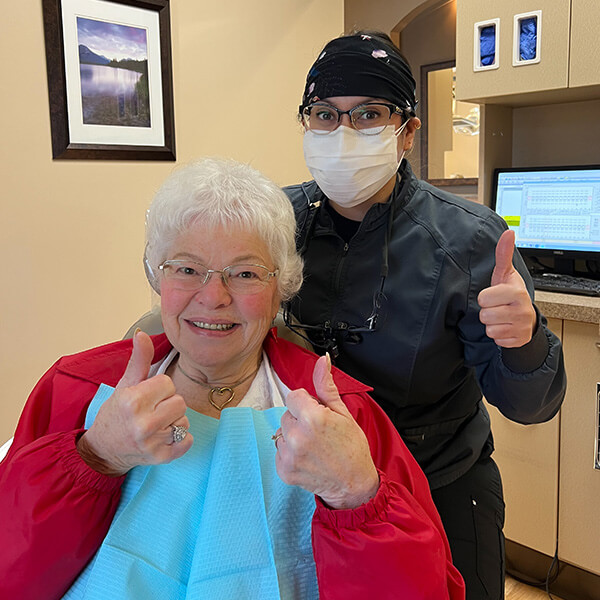 A senior woman patient sitting while a Gentle Smile Dentistry Staffer is next to her.