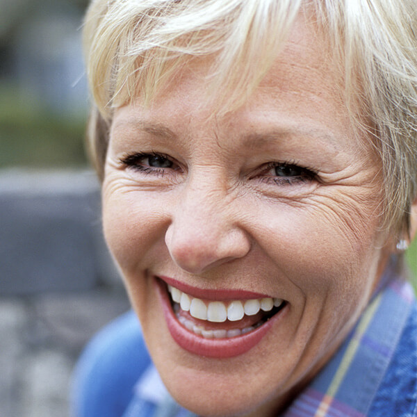 Blonde Senior Woman smiling outdoors.