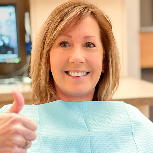 Blond patient woman smiling an giving a thumb up.