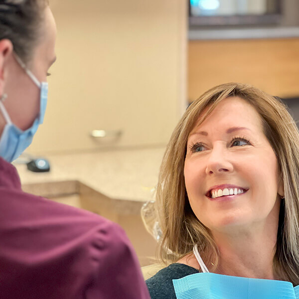 A patient woman smiling while looking at Gentle Smile Dentistry Staff.
